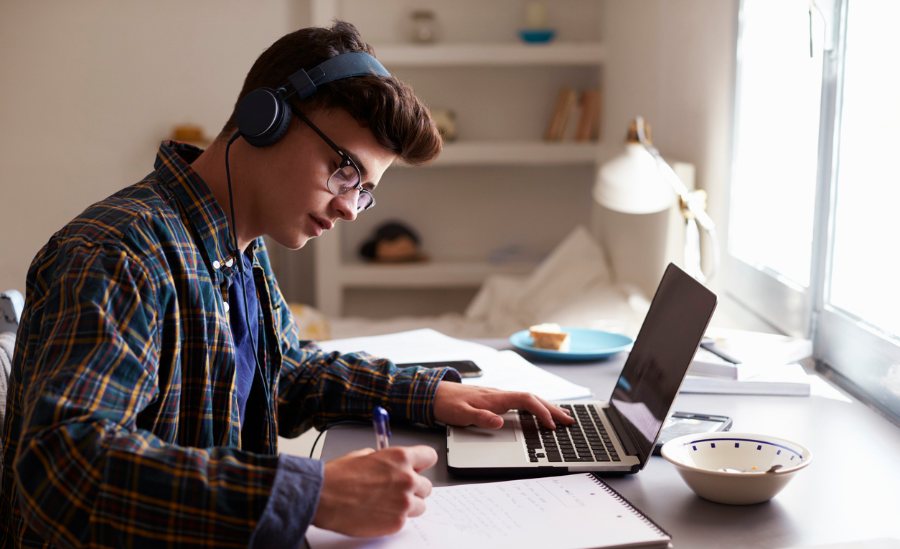 Young man learning on laptop with headphones